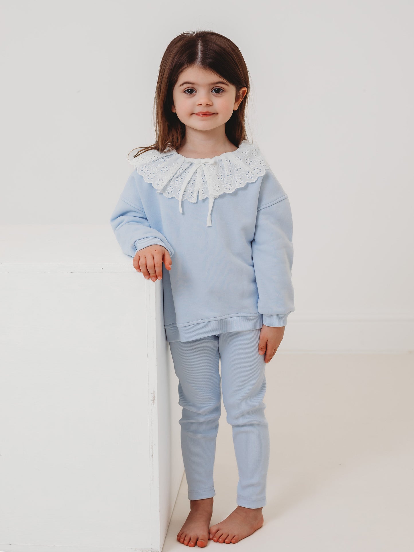 Kids light-blue top and ribbed leggings set with lace frill collar, standing pose