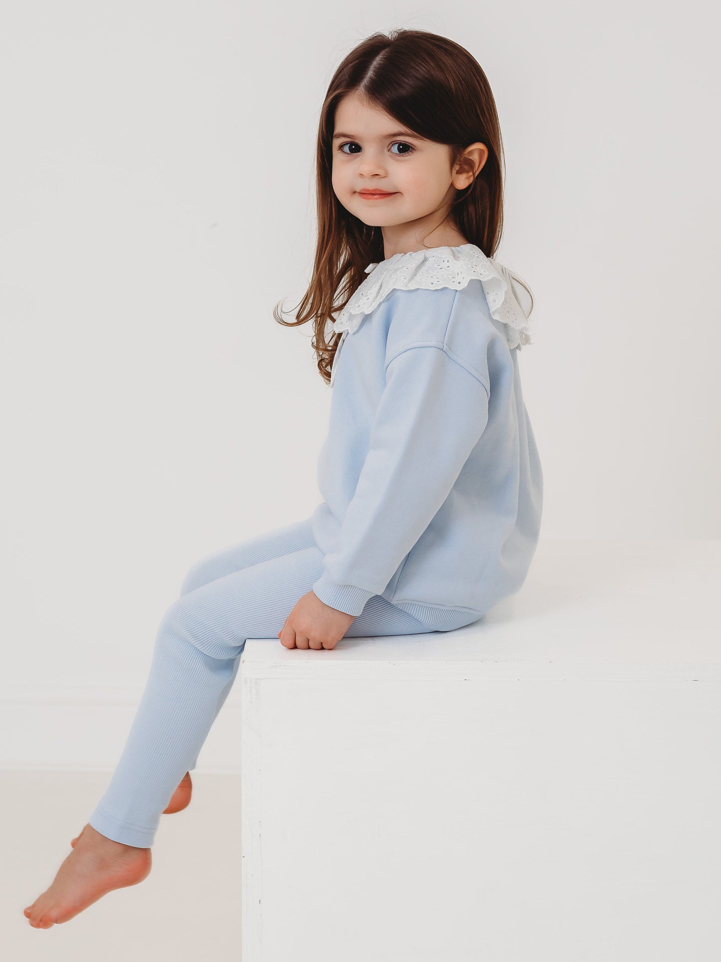 Light-blue kids top and ribbed leggings set, side view of lace frill collar