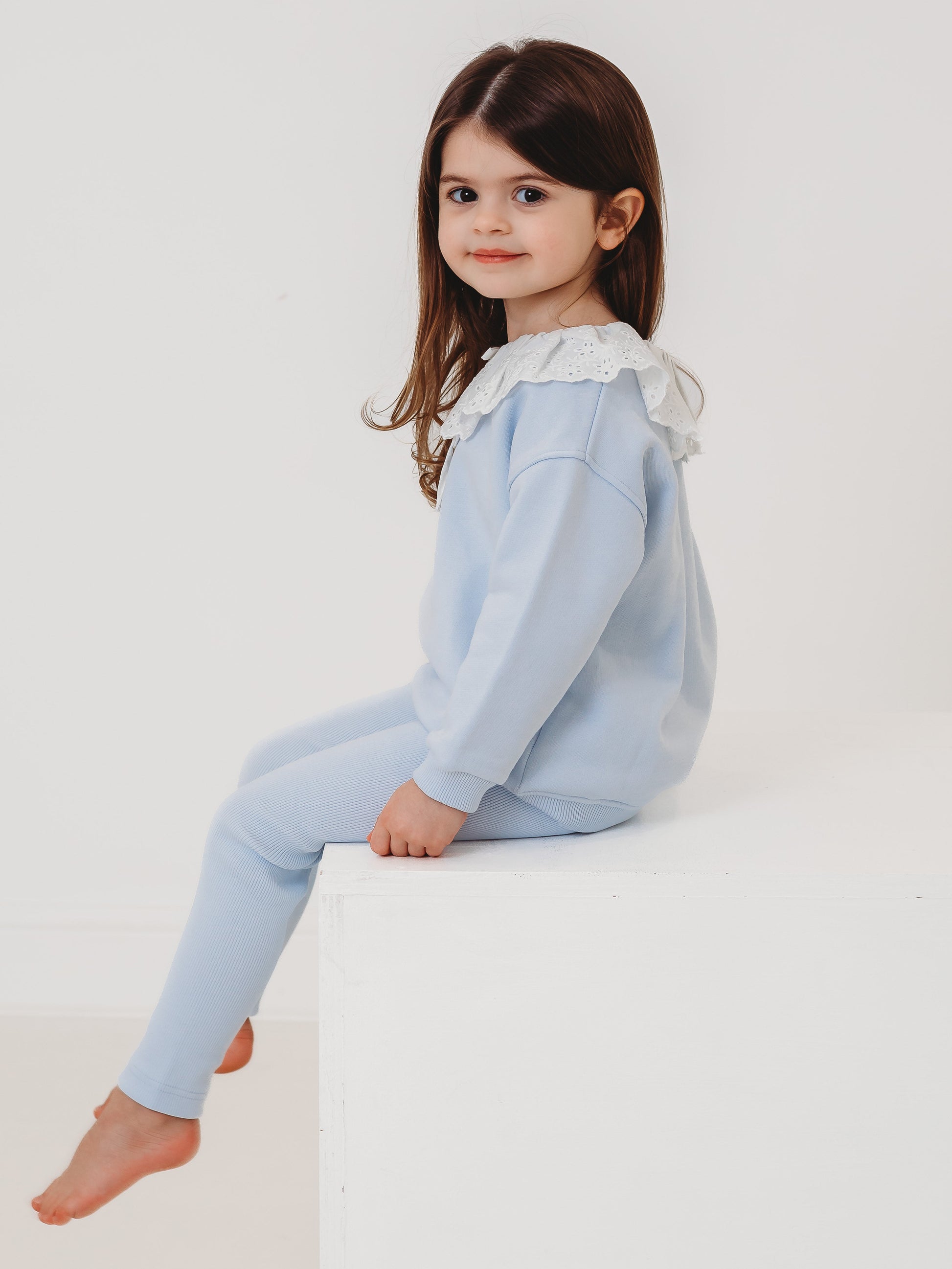 Light-blue kids top and ribbed leggings set, side view of lace frill collar