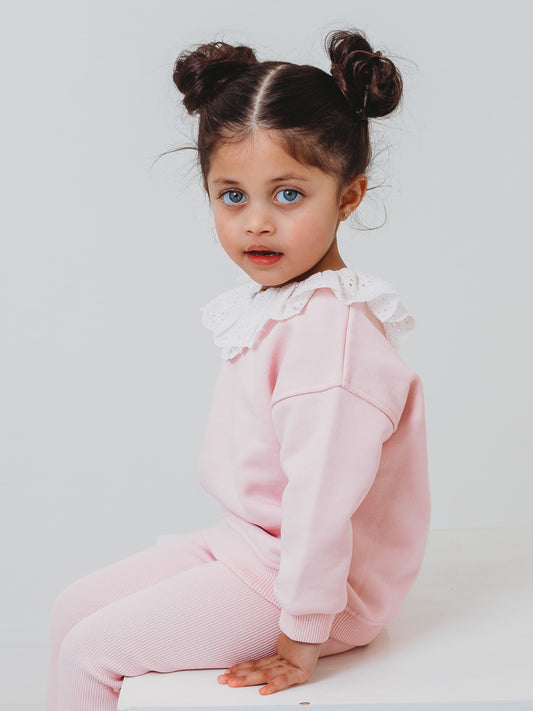 Pink frill-collar top with anglaise detailing and ribbed leggings, side view