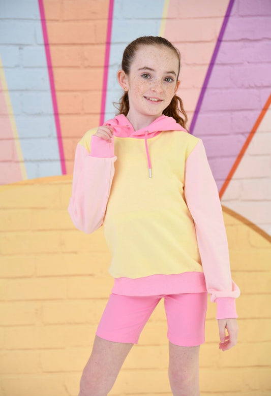 Young girl wearing a pink and yellow outfit with a colorful geometric background