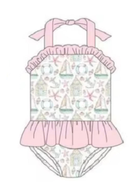 Girls one-piece swim suit with pink tie straps, frilled neckline, and allover maritime print