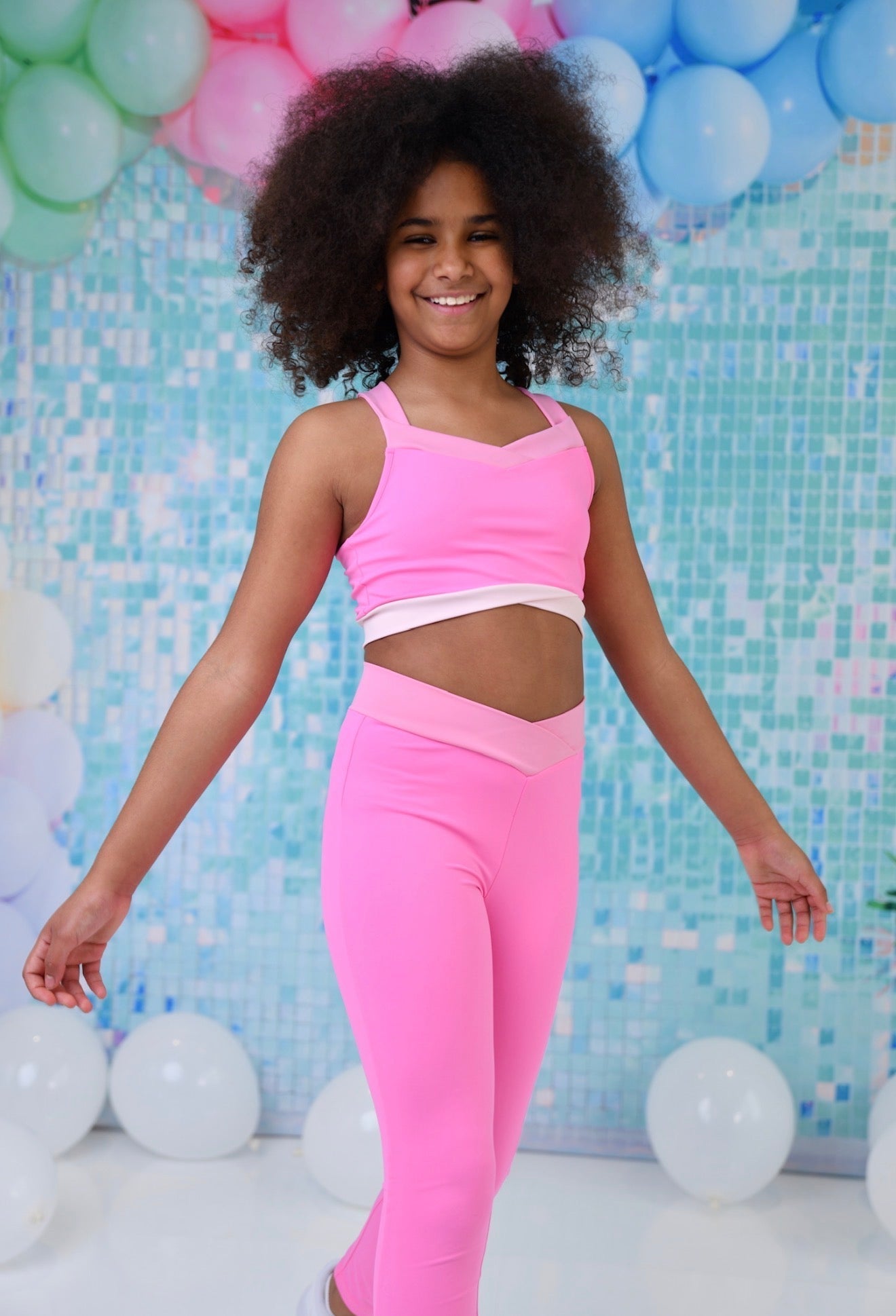 Girls' bright pink crop top and leggings set, front view with cutout waist