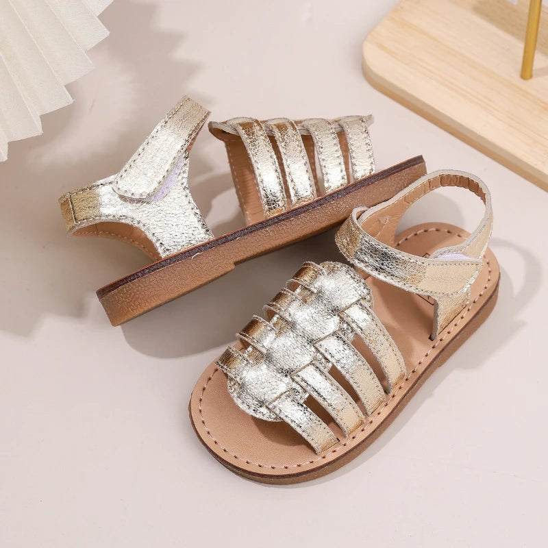 Girls gold metallic open-toe sandals with wide toe straps and flat brown outsole