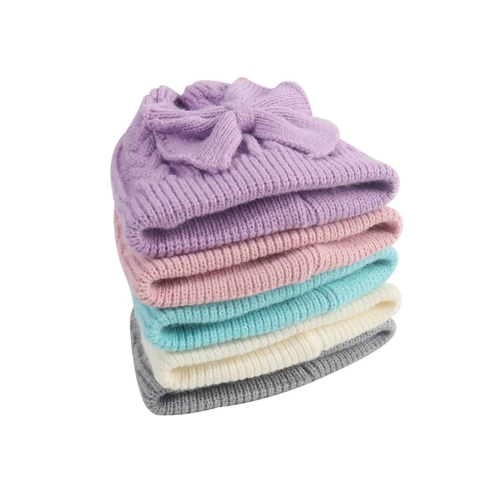 Stacked knitted beanie hats with bowknot in lilac, turquoise, cream, and gray