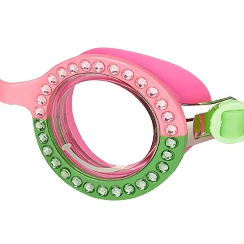 Pink swim goggles close-up with round lens and green rhinestone outer border