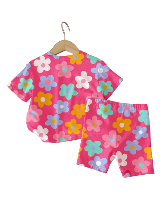 Children's pink floral outfit on a wooden surface with decorative items.