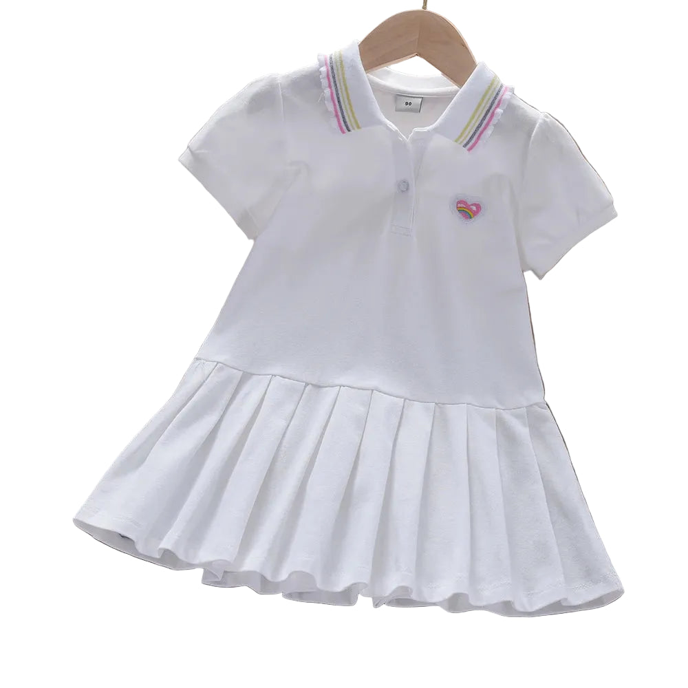 White children's dress with rainbow heart design on a wooden surface