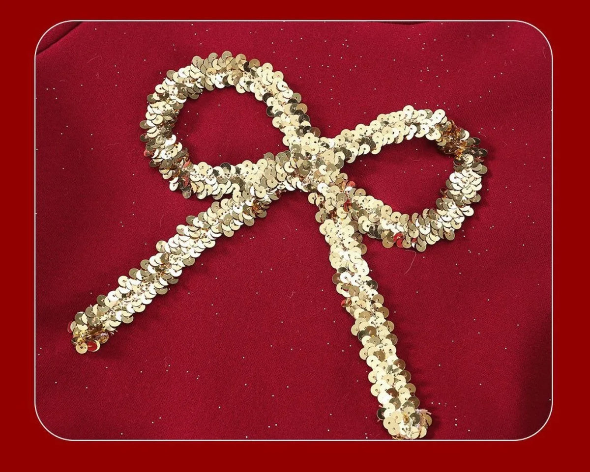 Close-up of gold sequin bow applique on red velvet girls dress