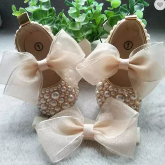 Ivory baby pram shoes with large bows and gold pearl embellishment