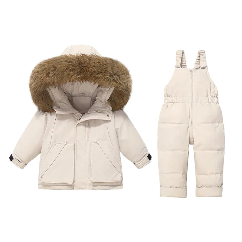 A children's winter outfit set consisting of a cream-colored puffer jacket with a large brown faux-fur trimmed hood and matching cream-colored puffer bib overalls, displayed on a solid light gray background.