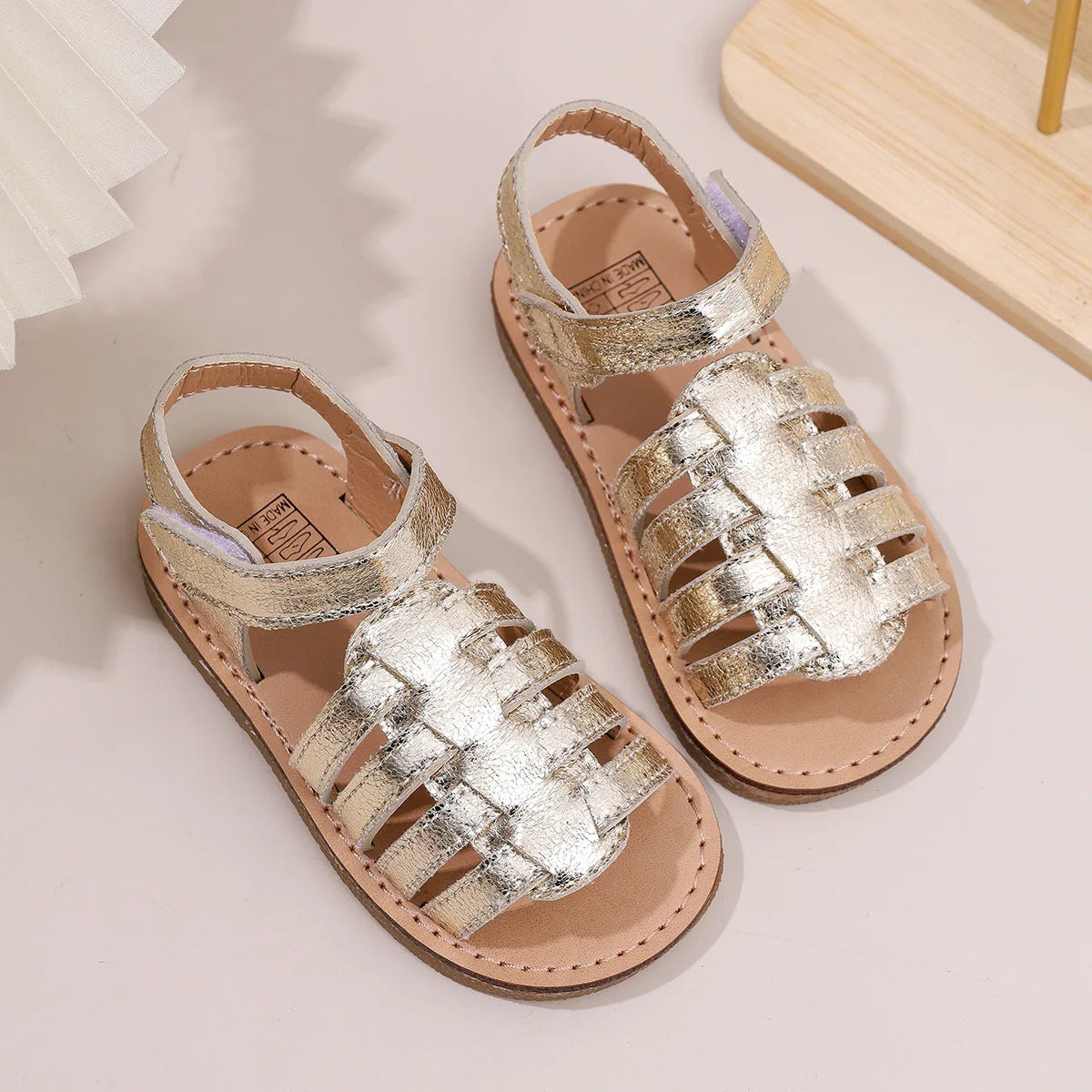 Girls gold metallic open-toe sandals with crisscross straps and hook-and-loop closure, flat sole