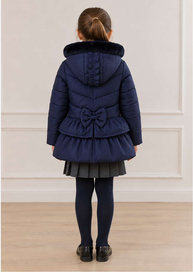 A young girl modeling a navy blue quilted winter coat, shown from both the front and back views against a neutral indoor wall and wood floor.