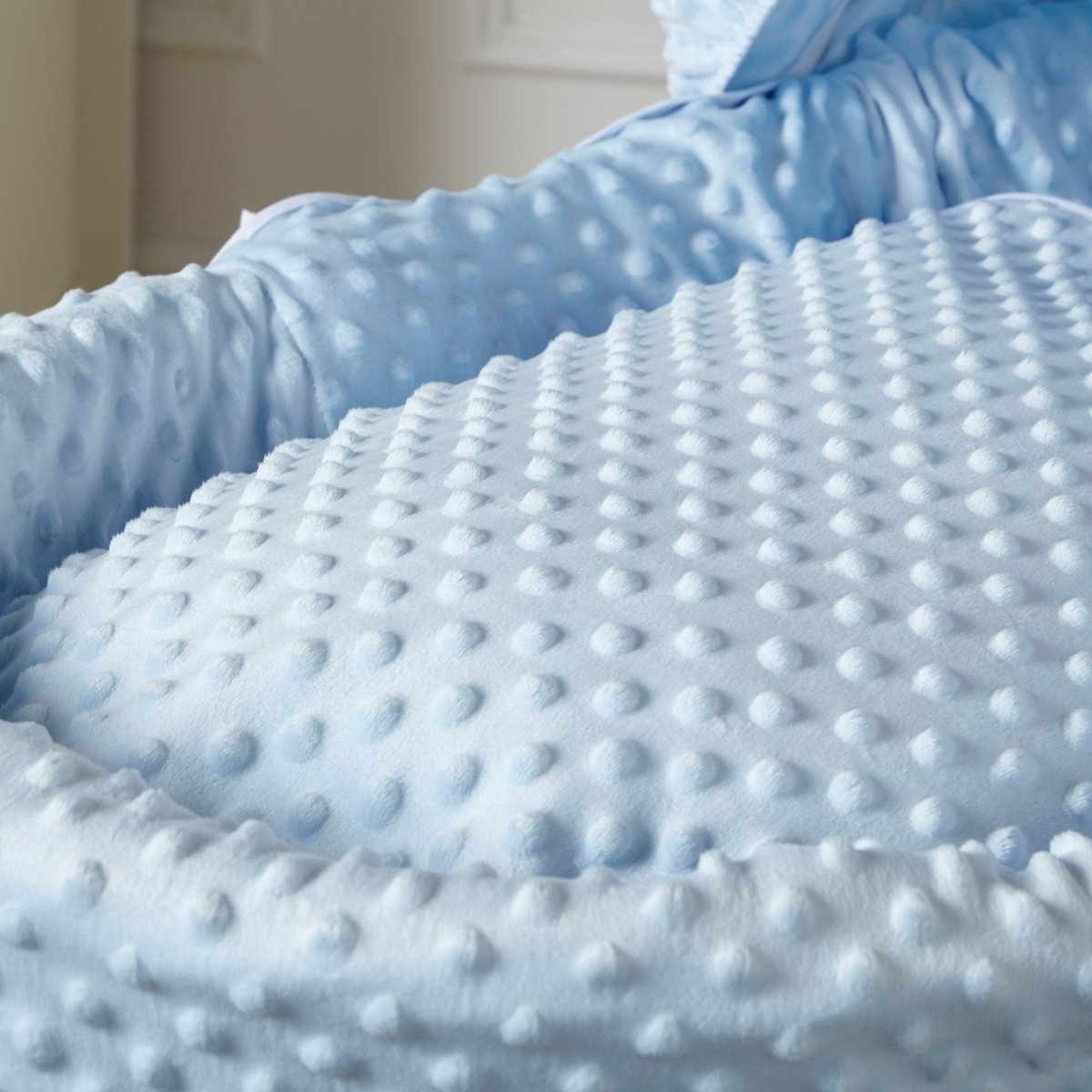 Close-up of blue dot-textured Moses basket mattress padding and quilted fabric