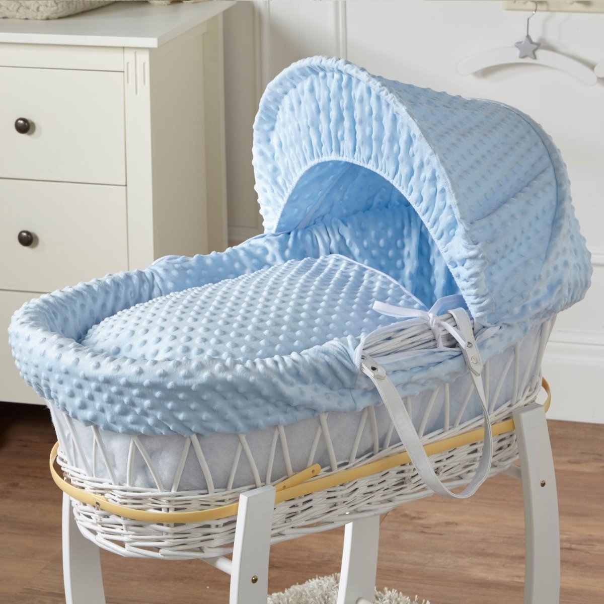 Blue padded Moses basket with canopy hood on a white stand, woven wicker sides
