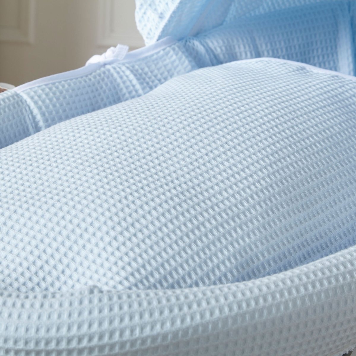 Close-up of blue waffle fabric mattress and hood for Moses basket