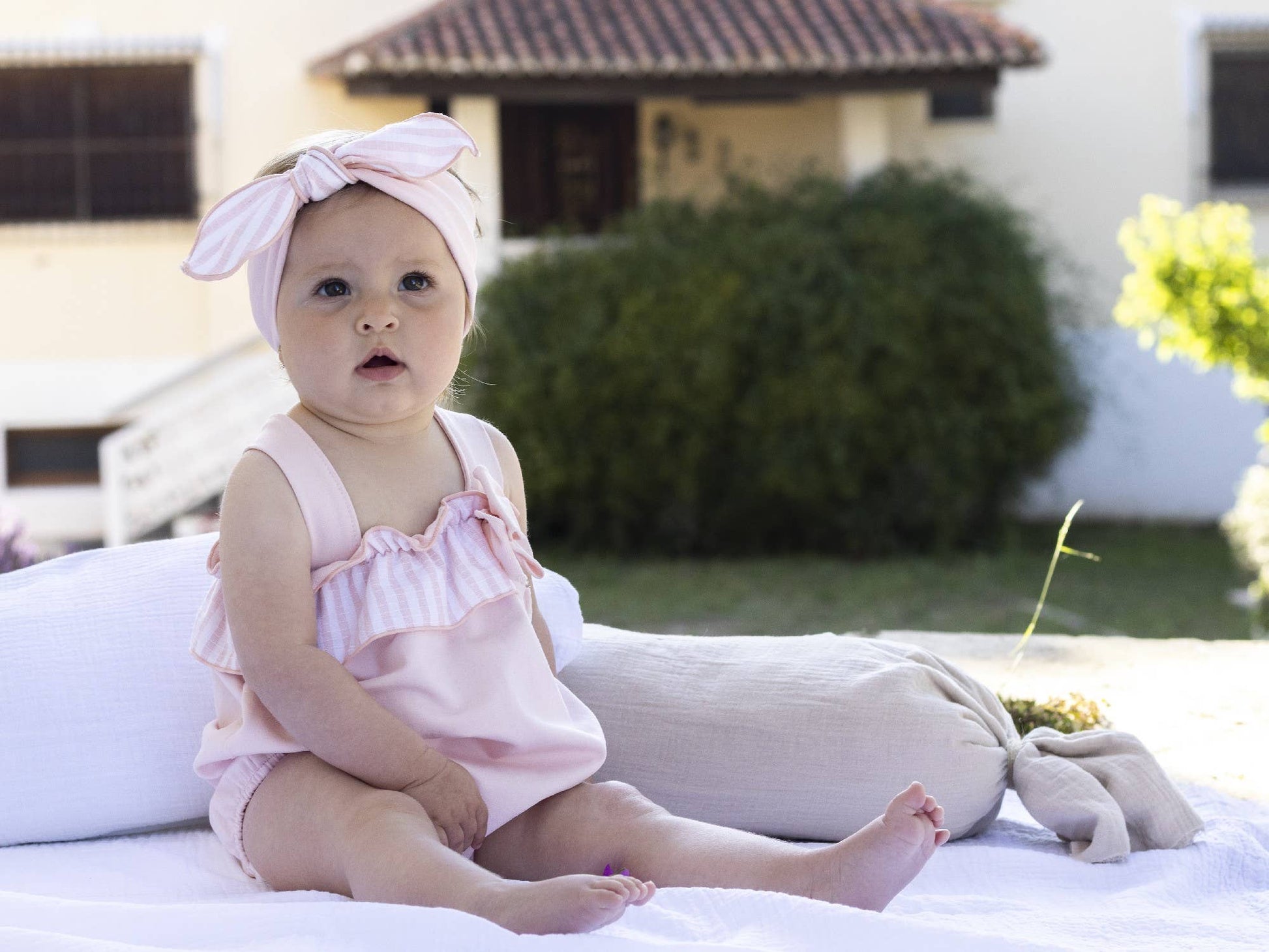 Baby girl dungaree with pink-and-white striped frills and tied bow straps