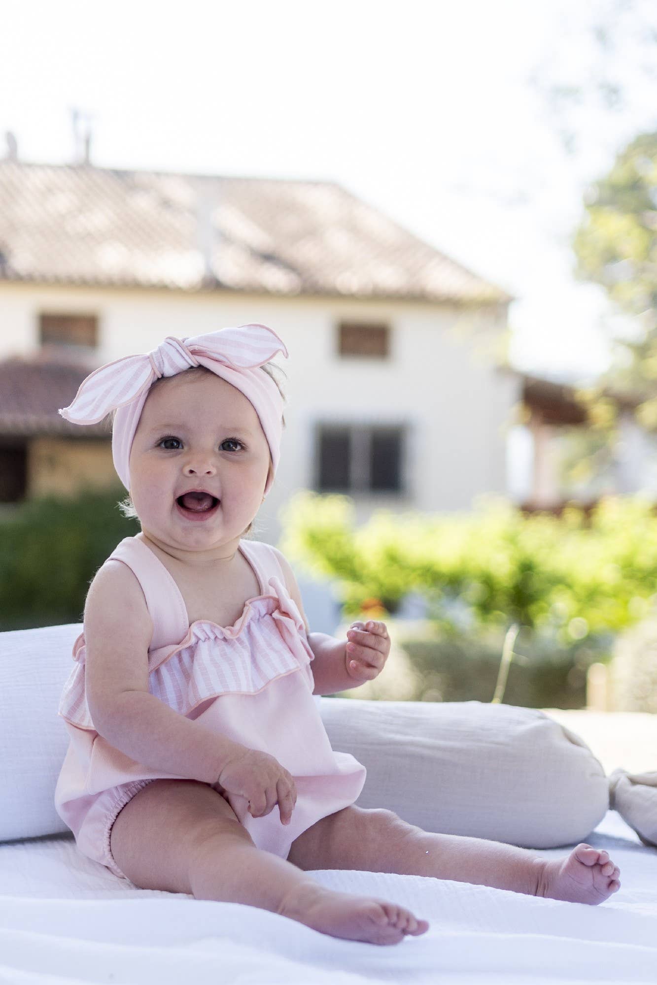 Pink dungaree romper with flutter straps, striped ruffle, and bow detail