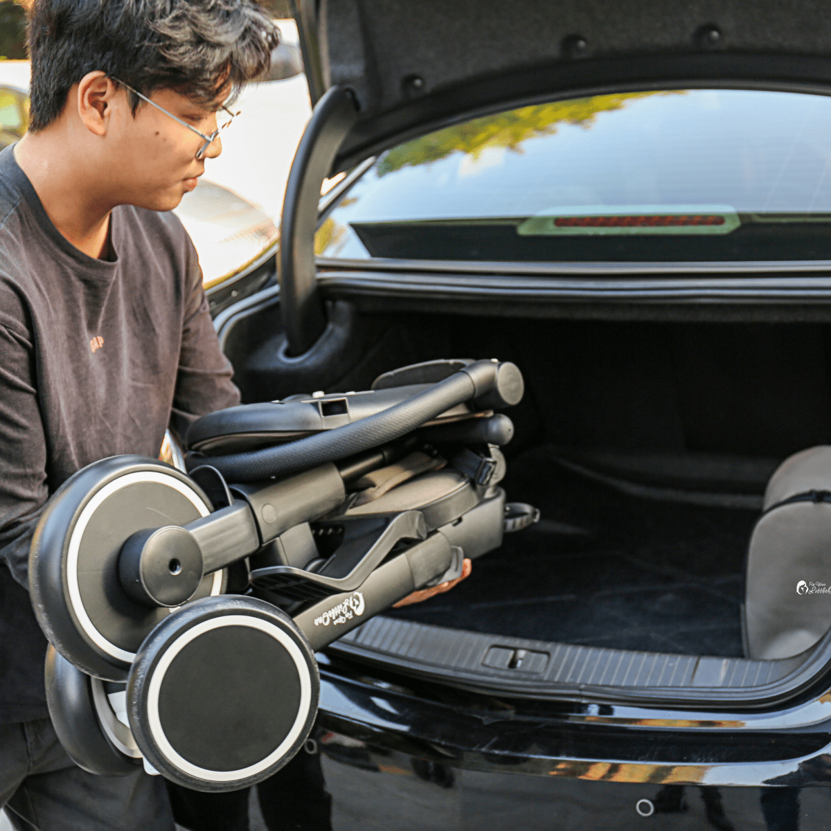 Jet black trike at car trunk opening, showing front wheels and handlebar