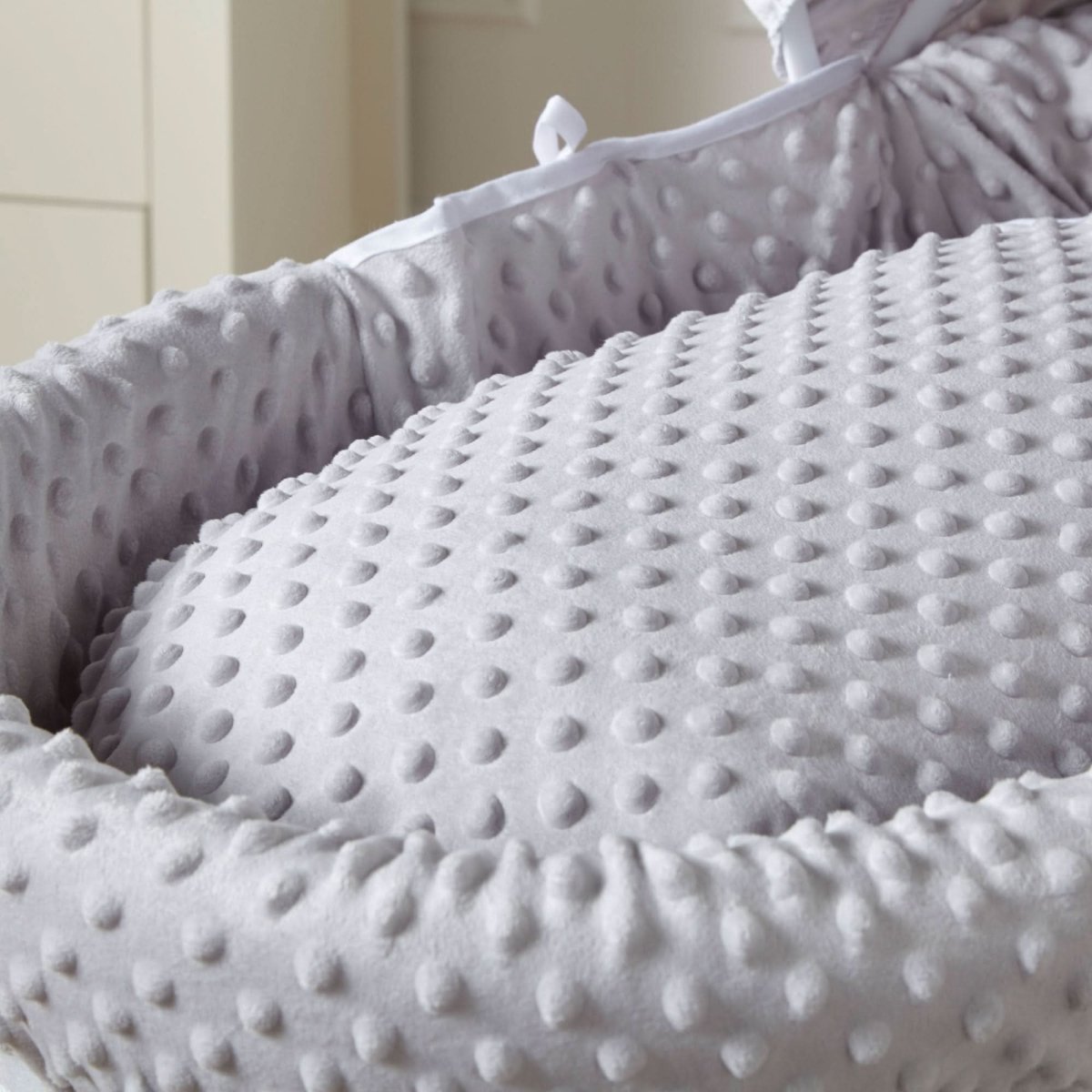Close-up of grey textured padded Moses basket liner and mattress bedding