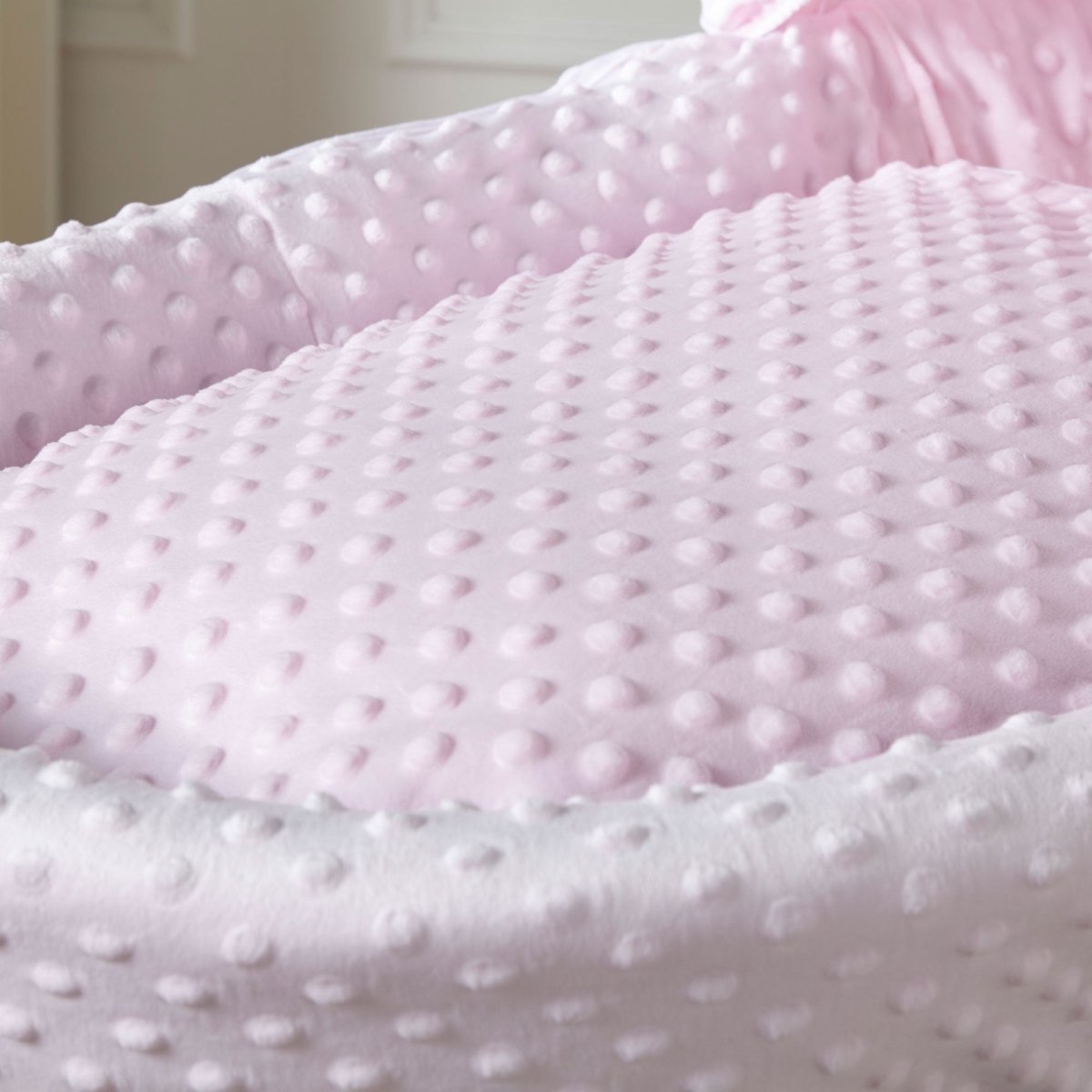 Close-up of pink moses basket padded mattress with textured dotted fabric