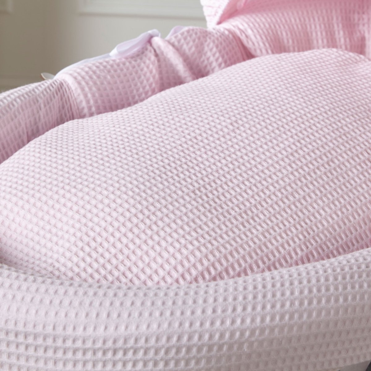 Pink waffle-textured Moses basket mattress pad with padded sides