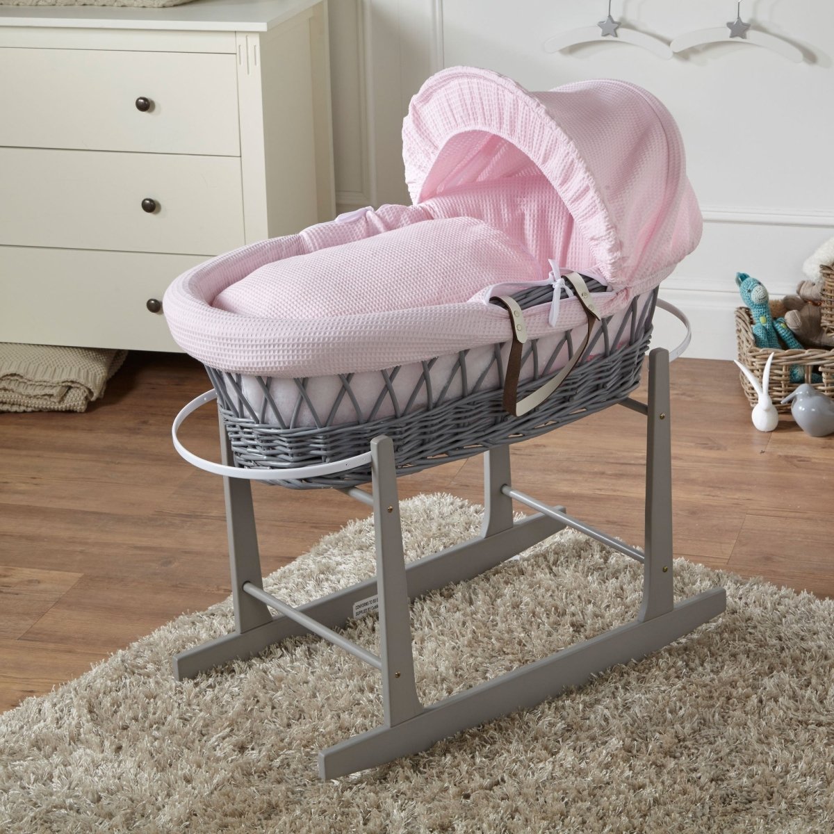 Grey wicker Moses basket with pink waffle padded liner and rocking stand