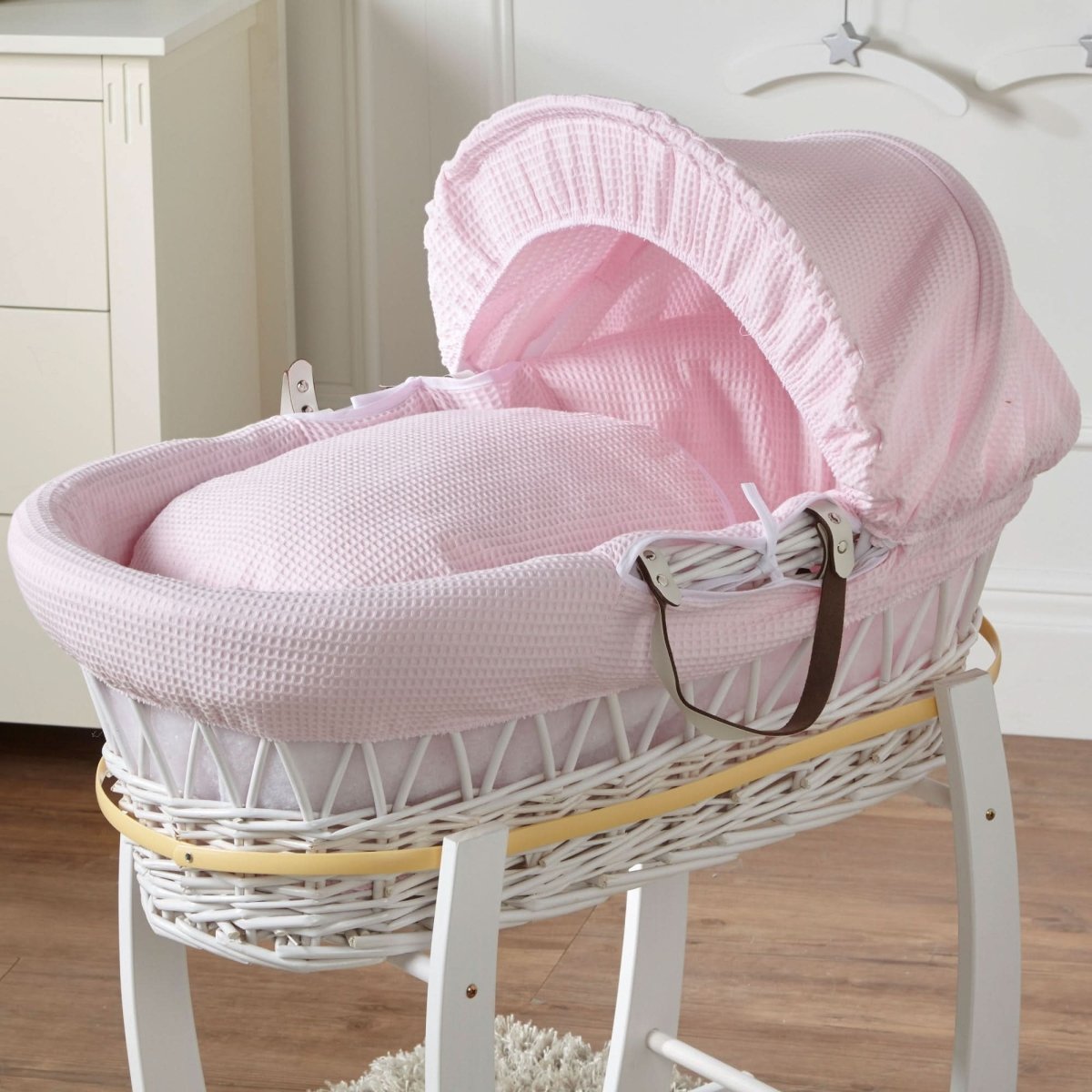 Pink Moses basket with wicker sides, padded base and arched hood on stand