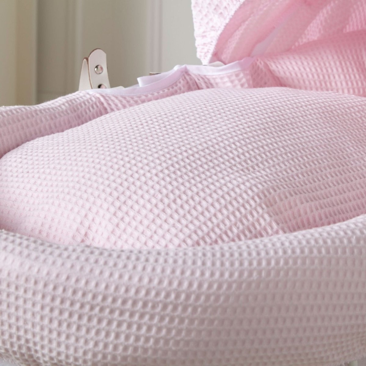 Close-up of pink waffle-texture padded Moses basket cover and hood