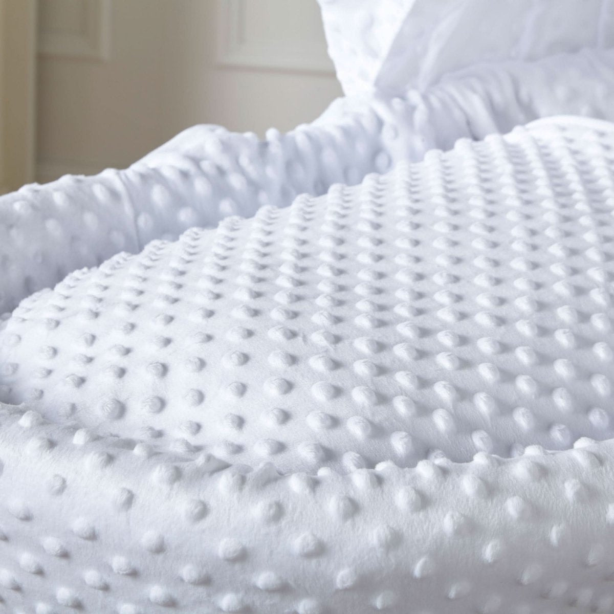Close-up of white dimple-textured padded Moses basket bedding