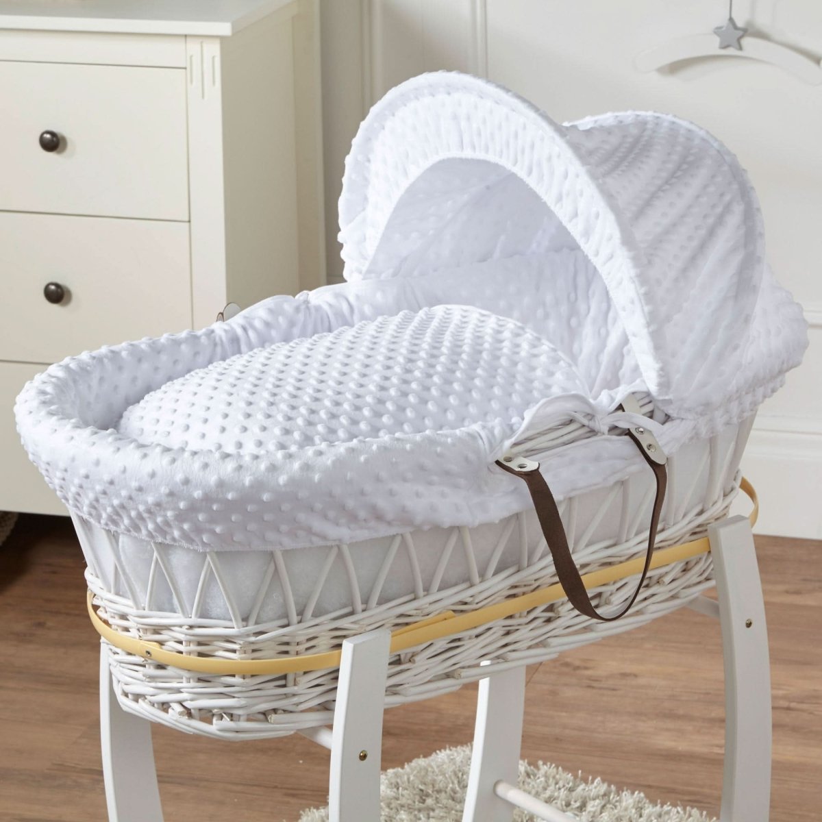 White Moses basket on stand with woven wicker sides and white padded insert