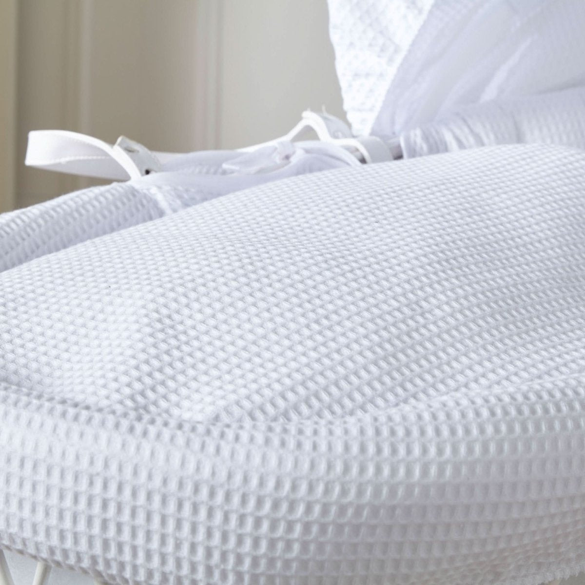 White waffle-textured padded Moses basket mattress and hood detail