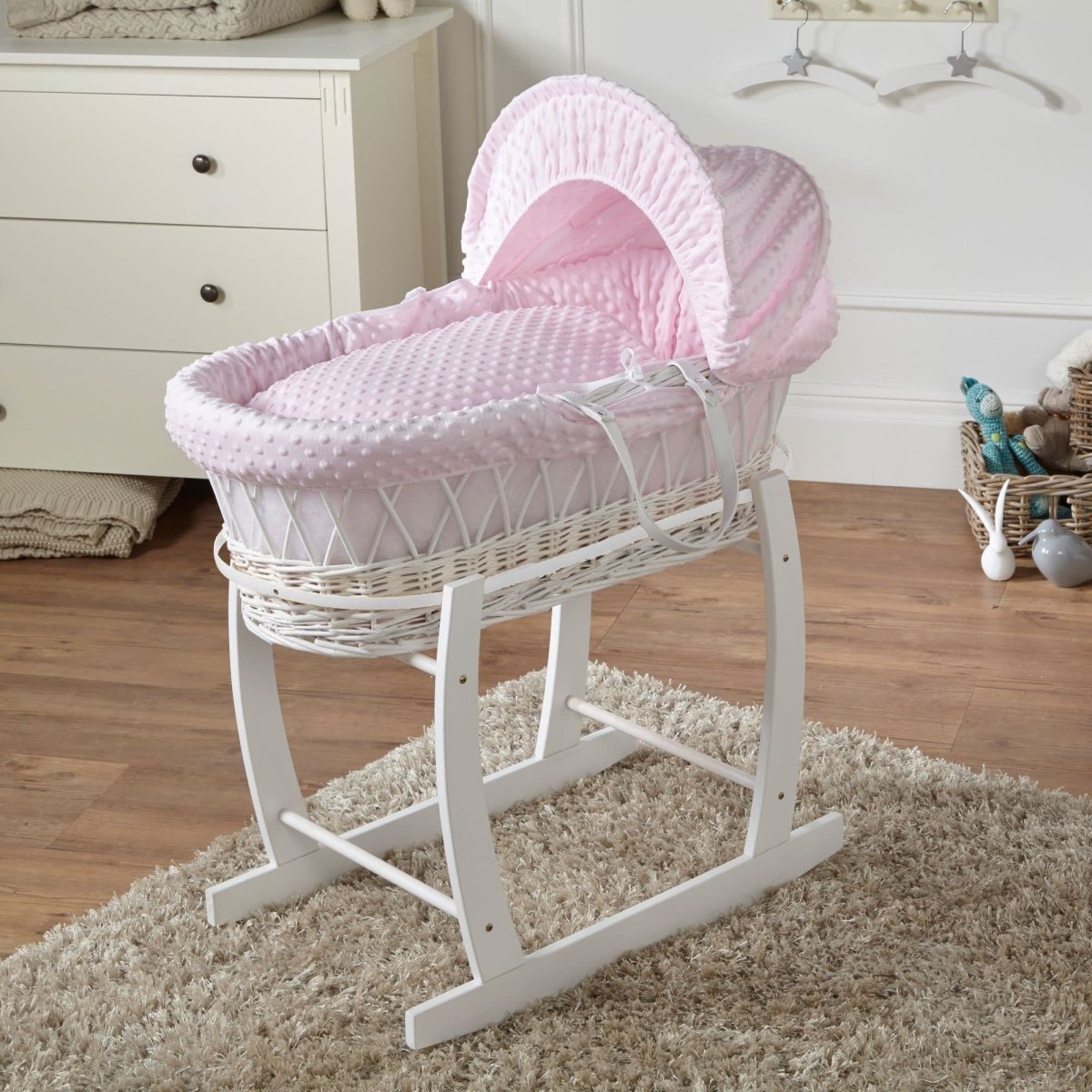 Pink Moses basket on stand with pink textured bedding and curved fabric hood